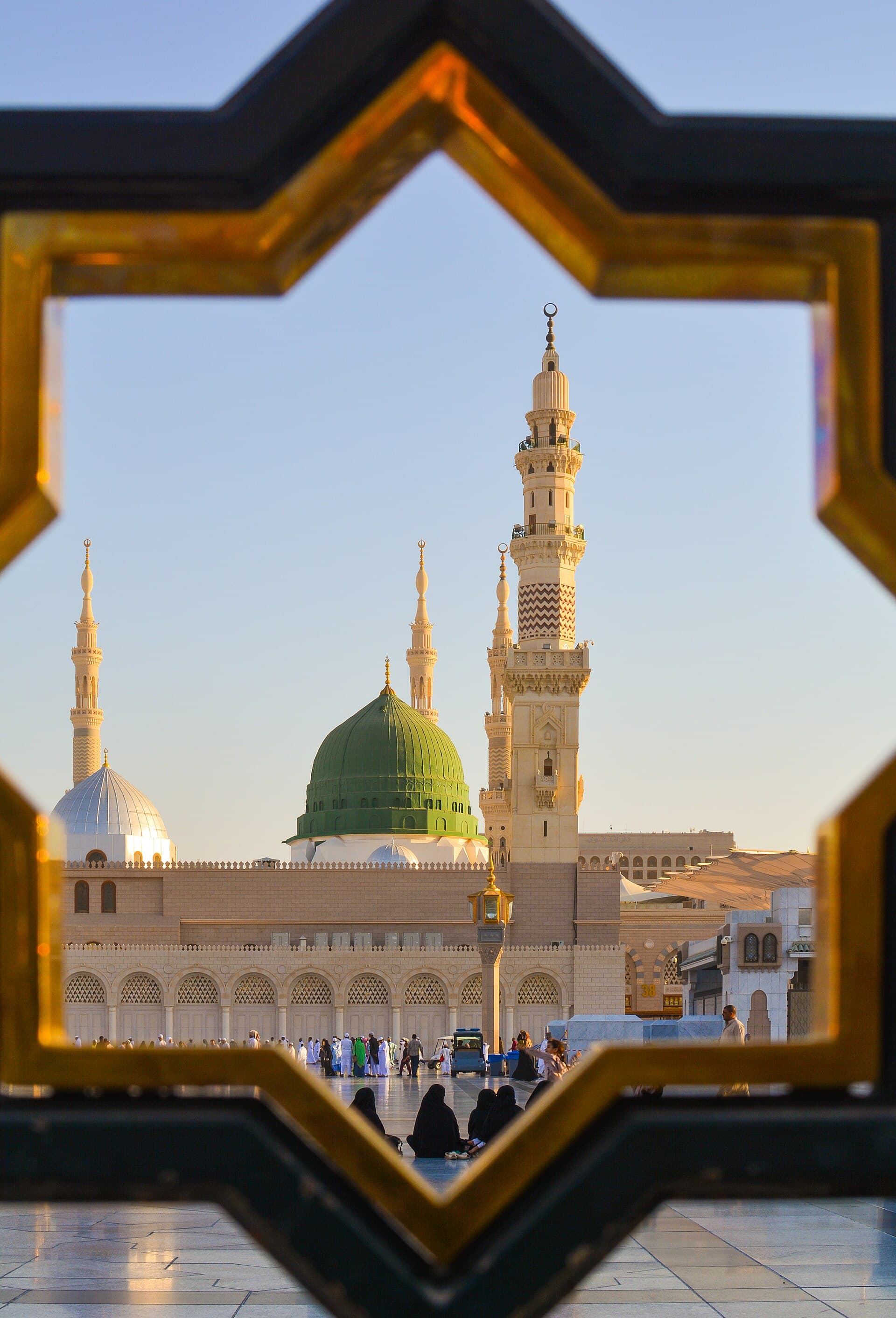Die grüne Kuppel und Minarette der Prophetenmoschee in Madinah, eingerahmt von einem islamischen Fenster